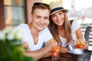 Happy guy and his girlfriend sitting in cafe on summer day