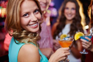 Aantrekkelijke vrouw met een cocktail in de hand die flirterig over haar schouder kijkt